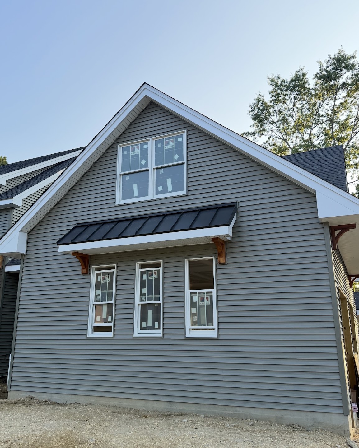 Black metal accent roof above windows on a gray house