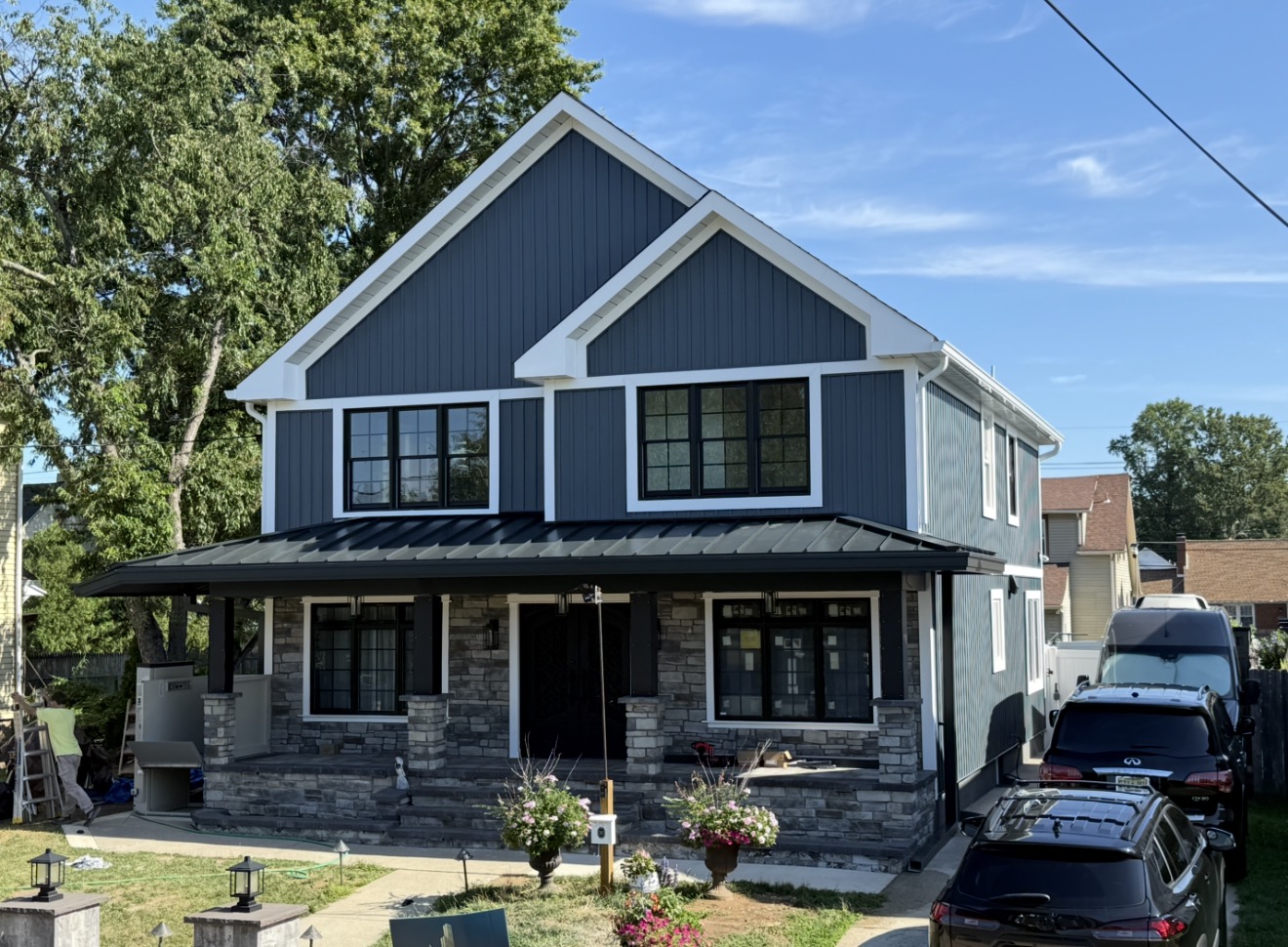 Charcoal standing-seam porch roof on a blue and stone home from Forge’s project gallery